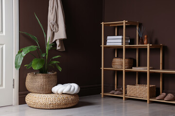 Stylish wicker pouf with houseplant and cushion at home
