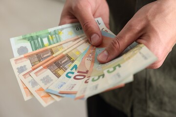 Man counting his money indoors, closeup view