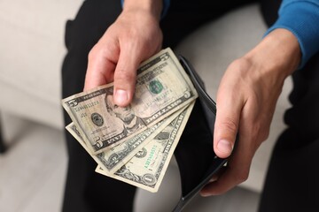 Man putting money into wallet indoors, closeup