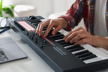 Man working with MIDI keyboard at white table indoors, closeup