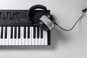 MIDI keyboard with headphones on white table, top view