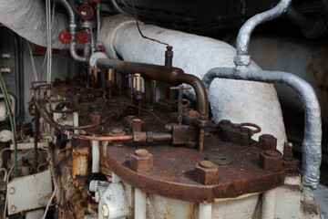 A detailed close-up of old and rusty industrial machinery, likely from a factory or an engine room. 