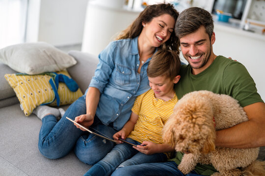 Joyful Caucasian family spending time together with digital devices and dog at home.