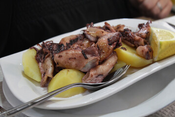 Exquisite calamaretis with onion, accompanied by boiled potatoes, a delicious Galician dish.