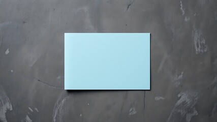 A minimalist composition featuring a clean light blue rectangular card placed on a textured dark gray concrete surface with subtle cracks