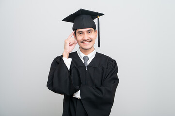 A young man in a graduation gown and cap smiles at the camera, striking a confident pose to celebrate his academic achievement on graduation day.