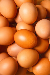 A close-up shot of a multitude of brown chicken eggs, filling the entire frame