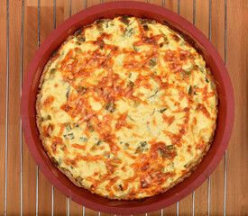 A top-down shot shows a baked cheese and green onion pie with a golden-brown, slightly crispy top in a red baking dish on a wire rack
