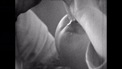 Film archive, Small child drink water from glass, close up. Mother watching closely as girl toddler drinks fresh water. Thirsty kid face portrait at home. Vintage old archival family retro 1960s