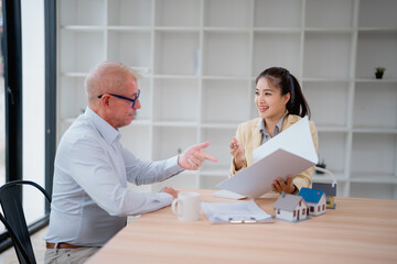 Real estate agent showing project to client discussing contract and agreement sitting at desk in...