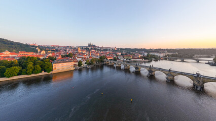 Bright colors fill the sky as the sun rises over Prague, illuminating the Vltava River and its...