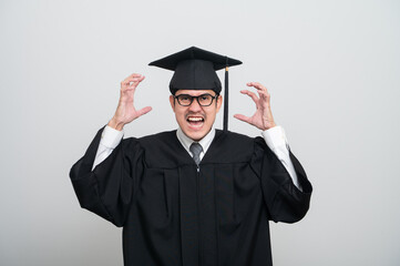 A young man in a graduation gown and cap smiles at the camera, striking a confident pose to...