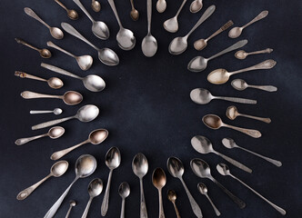 Set of different spoons. Silver cutlery on a black background. Spoon on the table. Circle frame top...