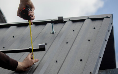A man is installing solar panel mounts on the roof. Selective focus