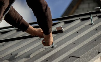 A man is installing solar panel mounts on the roof. Selective focus