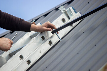 A man is installing solar panel mounts on the roof. Selective focus
