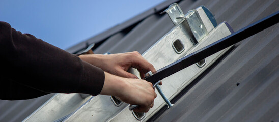 A man is installing solar panel mounts on the roof. Selective focus