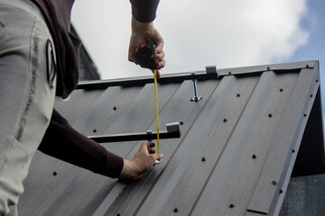 A man is installing solar panel mounts on the roof. Selective focus
