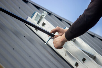 A man is installing solar panel mounts on the roof. Selective focus