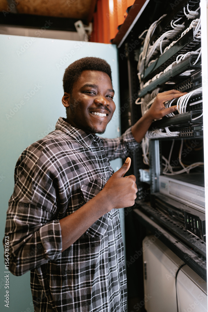 Poster technician organizes network equipment while smiling in data center during afternoon hours