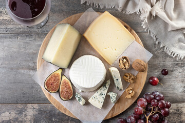 board of different cheeses with nuts, figs and grape on wooden table. Top view