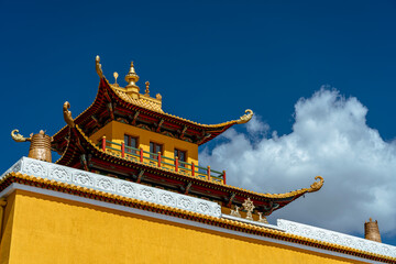 Bright yellow Buddhist temple with ornate golden roof under deep blue sky in Mongolia