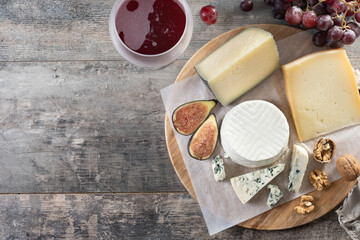 board of different cheeses with nuts, figs and grape on wooden table. Top view. Copy space