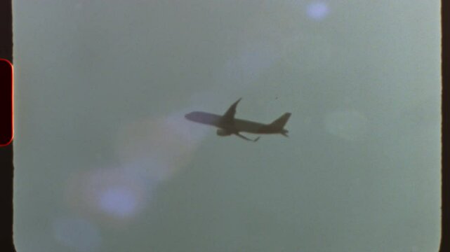 Filmed on super 8 film Vintage style commercial passenger jet soaring across cloudy sky, captured with nostalgic film grain and authentic light leaks reminiscent of analog cinematography