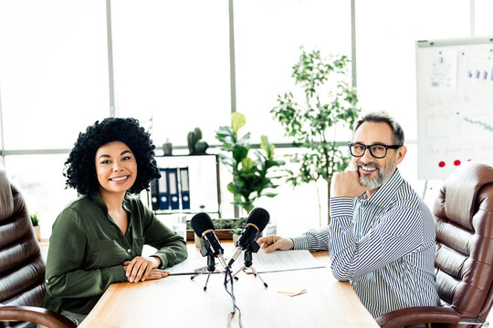 Two professionals collaborate on a podcast in a modern office workspace showcasing diversity and teamwork
