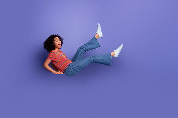 Young energetic woman in vibrant casual attire appearing cheerful on a purple background expressing...