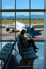 Silhouette of woman working on laptop and waiting for flight in the Airport-Busy airport airfield...