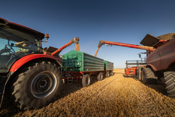 Farm machinery working together in a golden wheat field.