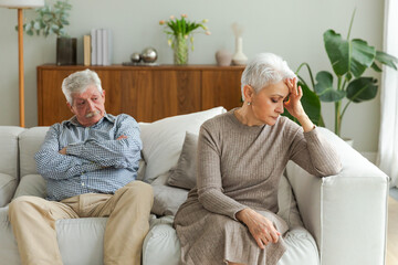 Marriage crisis relationship problems. Old couple quarreling. Sad mature disappointed woman sitting away from husband after having quarrel. Senior couple not talking having problems in relationship