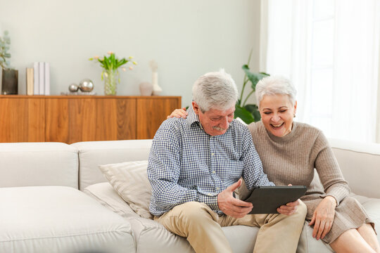 Senior old couple with tablet watching video online. Husband wife spending time together at home. Happy modern mature senior couple using tablet for family entertainment. Old people modern technology