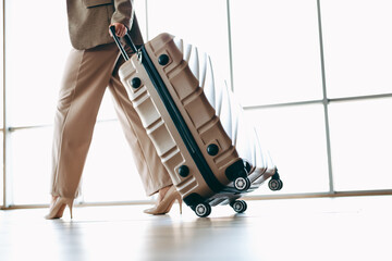 Stylish businesswoman walking with a suitcase in a bright modern interior