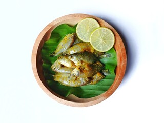 Marinated siamese gourami fish (Trichogaster pectoralis) on banana leaf and wooden plate with white background