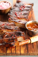 Delicious spare ribs, sauce and brush on grey table, closeup
