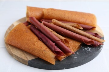 Delicious fruit leather rolls on white table, closeup