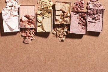 Beautiful eyeshadow refill pans on brown background, flat lay. Space for text