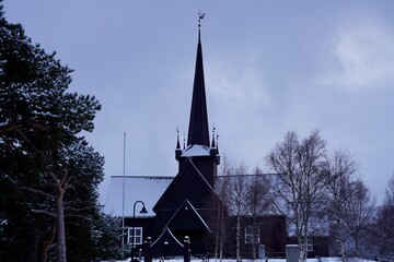 The tall spire of Lesja church pierces a cloudy winter sky at Lesja, Norway.