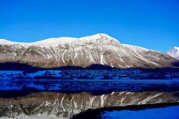 Snow covered mountains are rflected in the mirrorlike surface of the Isefjorden, near Aandalsnes,...