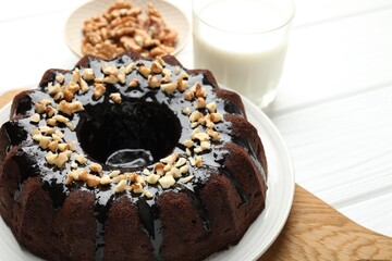 Delicious chocolate bundt cake with nuts and glass of milk on white wooden table, closeup