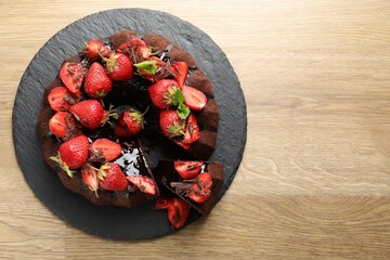 Delicious bundt cake with strawberries and chocolate shavings on wooden table, top view. Space for text