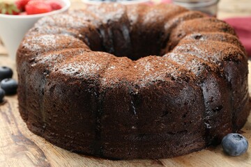 Delicious chocolate bundt cake with blueberries on wooden table, closeup