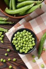 Fresh ripe green peas on wooden table, flat lay