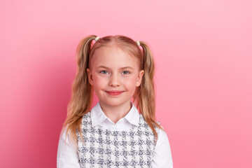 Adorable schoolgirl with ponytails wearing a white shirt and patterned skirt against a pink...