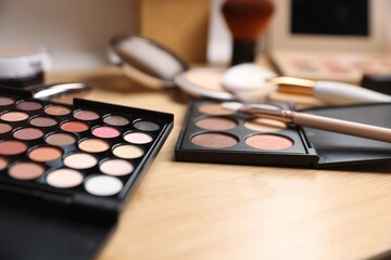 Different makeup products on wooden vanity indoors, closeup