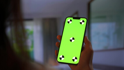 Hands holding smartphone with green screen layout
