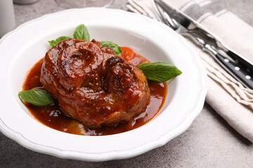 Traditional ossobuco dish with beef steak served on grey table, closeup