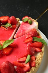 Delicious cheesecake with strawberries, sauce and mint on black table, above view